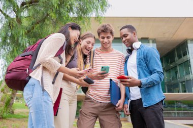 Akıllı telefonlarına bakan bir grup arkadaş kampüste interneti cep telefonuyla tarıyor.