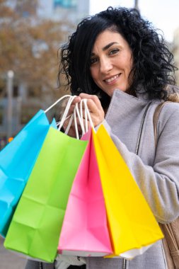 Dikey portre kadın alışverişi. Alışveriş torbalarıyla alışveriş yapan mutlu bir kadın. Tüketim, alışveriş, yaşam tarzı konsepti