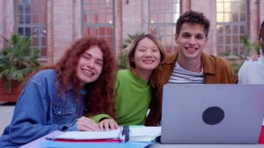 Genç öğrencilerden oluşan çok ırklı bir grup, notlarını paylaşıyor ve bir dizüstü bilgisayarla üniversite kampüsünde okuyor.