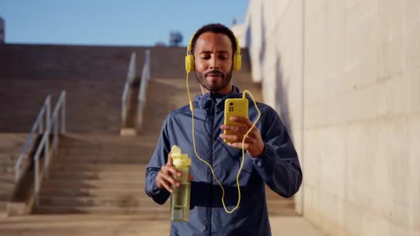 Egzersiz Yapmaktan Yorgun Kulaklıklı Atletik Bir Adam Cep Telefonu Uygulaması — Stok video