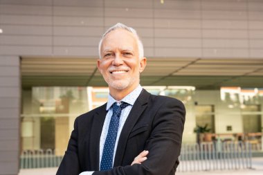 Profesyonel, olgun ve gülümseyen yönetici, gururlu avukat, takım elbiseli ve kravatlı iş adamı kameraya bakıyor..