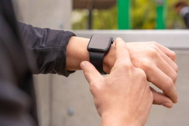 Zeki bir saate bakan genç bir sporcunun kısmi görüntüsü.