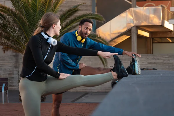 Active and fit male and female runners in leg warm-up stretching for running or cardio outdoors
