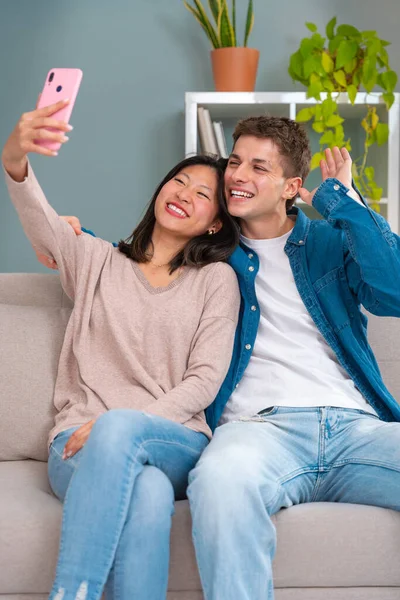 Young smiling multiracial friends taking a selfie in living room. Concepts of youth, peoples lifestyle, diversity, urban life