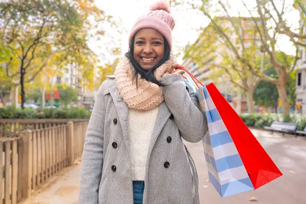 Happy young latin woman holding shopping bag outdoors - Close-up of a smiling latina girl in the city