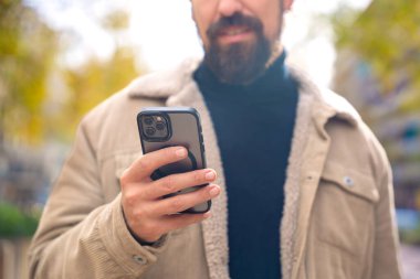  Mutlu adam cep telefonuna bakıyor, gülümsüyor, uygulama kullanarak mesaj yolluyor. İnsan duyguları kavramı, yüz ifadesi. 