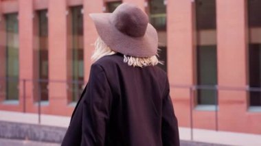 Şapkalı ve çantalı mutlu kadın ofisin girişine doğru yürüyor..