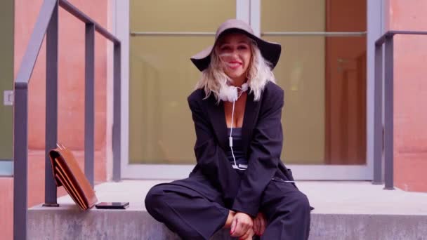 Şapkalı Çantalı Mutlu Beyaz Kadın Açık Ofis Girişinde Merdivenlerde Oturuyor — Stok video