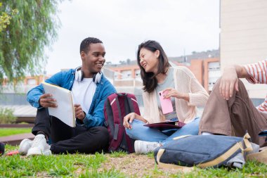 Farklı etnik çeşitlilikteki arkadaşlar dersten sonra dışarıda dinleniyorlar. Üniversite yaşam konsepti