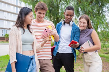 Akıllı telefonlarına bakan bir grup arkadaş kampüste interneti cep telefonuyla tarıyor.