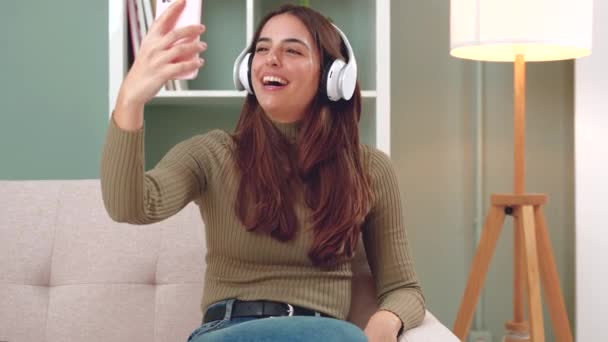 Kulaklık Takan Mutlu Genç Bir Kadının Cep Telefonuyla Konuştuğu Evden — Stok video