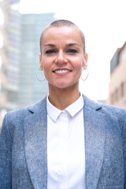  Beyaz iş kadını, dış mekanda duran takım elbiseli kameraya ciddi ciddi bakıyor. Düşünceli bir ifadeyle genç bir avukatın bakışları.