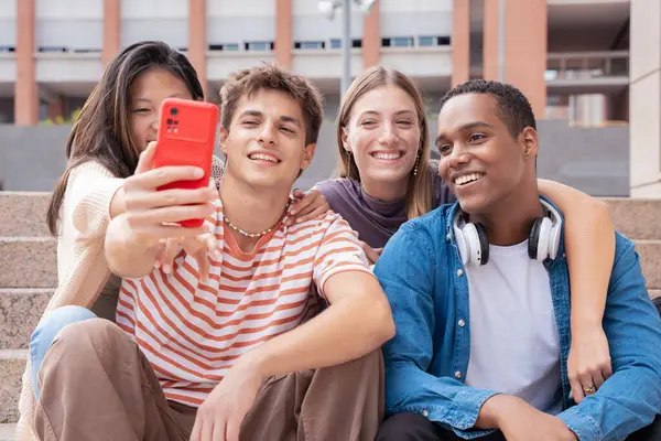 Çok ırklı genç arkadaşlar kampüste selfie çekiyorlar. Şehirde toplanan çok ırklı öğrenciler, gençlik kavramları, insan yaşam tarzı, çeşitlilik, gençlik ve şehir hayatı