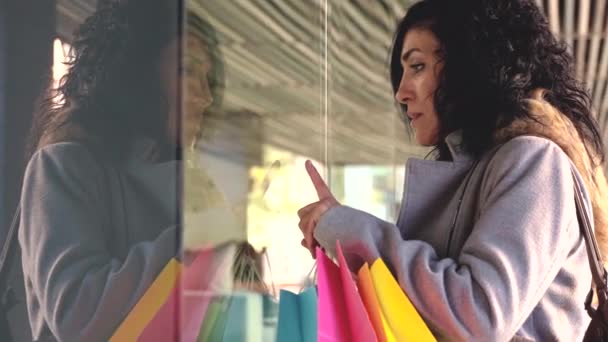 Kobieta Zakupy Centrum Handlowym Wskazując Nowe Ubrania Oknie Pokazując Dobrą — Wideo stockowe