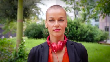 Beyaz iş kadını kameraya gülümseyen kulaklıklı bir kadın açık bir çalışma alanında duruyor. Olumlu bakışları olan genç bir avukatın önü.