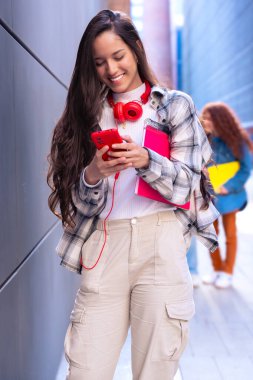 Elinde not defteri olan genç bir öğrenci akıllı telefon uygulamaları ve kablosuz teknolojisi olan sosyal ağlar kullanıyor..