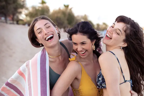 Neşeli çoklu etnik arkadaşlar sahilde mutlu bir şekilde kameraya bakıyorlar..