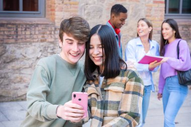İnternette sohbet etmek için cep telefonu kullanan mutlu çok ırklı öğrenciler. Üniversite yaşam konsepti