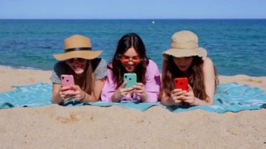 Bir grup gülümseyen, etnik çeşitlilikte kadın tatilde. Güzel ve neşeli Z jenerasyonu kızları cep telefonlarıyla kameraya bakıp poz veriyorlar..