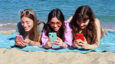 Bir grup gülümseyen, etnik çeşitlilikte kadın tatilde. Güzel ve neşeli Z jenerasyonu kızları cep telefonlarıyla kameraya bakıp poz veriyorlar..