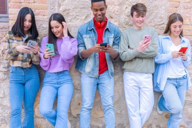 Akıllı telefonlarına bakan bir grup arkadaş kampüste interneti cep telefonuyla tarıyor.