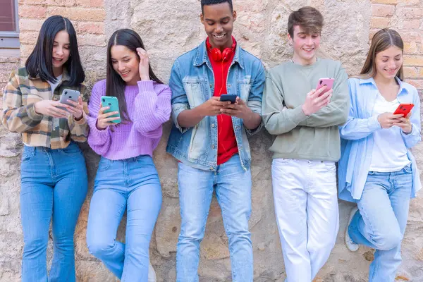 Akıllı telefonlarına bakan bir grup arkadaş kampüste interneti cep telefonuyla tarıyor.