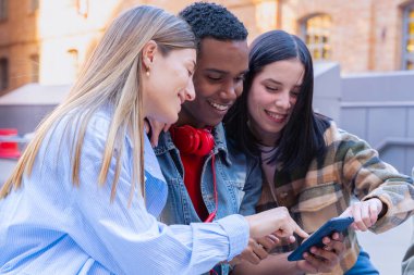 Akıllı telefonlarına bakan bir grup arkadaş kampüste interneti cep telefonuyla tarıyor.
