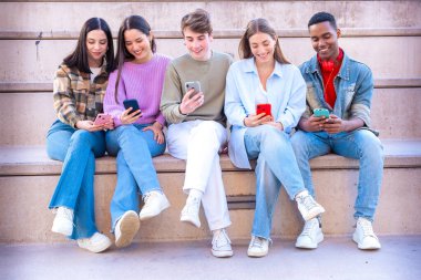 Akıllı telefonlarına bakan bir grup arkadaş kampüste interneti cep telefonuyla tarıyor.