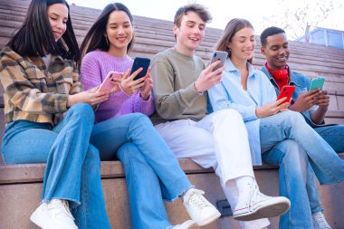 Akıllı telefonlarına bakan bir grup arkadaş kampüste interneti cep telefonuyla tarıyor.