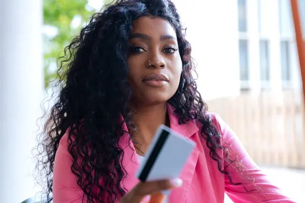 stock image African american young Businesswoman with credit card and cell phone sitting at a bar. Concept: Online shopping.