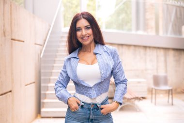 Beyaz bir iş kadınının dış mekanda duran takım elbisesiyle kameraya gülümseyen görüntüsü. Düşünceli bir ifadeyle genç bir avukatın bakışları.