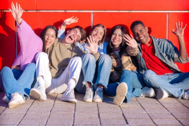 Beş çok ırklı arkadaş gülümsüyor ve neşeli ifadelerle kameraya bakıyor. Hevesli gençler toplandı