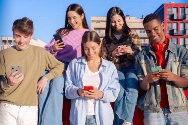 Akıllı telefonlarına bakan bir grup arkadaş kampüste interneti cep telefonuyla tarıyor.