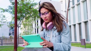  Üniversitedeki genç bir öğrenci eğitim uygulaması ile çalışmak için bir tablet kullanır. Modern öğrenimin, teknoloji entegrasyonunun ve öğrenci yaşamının özünü canlı bir akademik ortamda yakalamak.