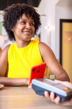 Dikey portre Mutlu Afrikalı Amerikalı kadın bir kredi kartı tutuyor ve ödeme yapıyor.