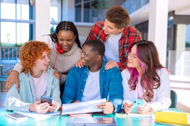 Kitaplar ve cihazlarla ortak bir proje üzerinde çalışan ve kütüphanede işbirliği yapan beş farklı öğrenciden oluşan bir grup..