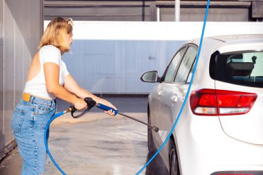 Görüntü, portre genç, gülümseyen, çekici bir kadın araba yıkama, araba yıkama, köpük temizleme, basınçlı su.