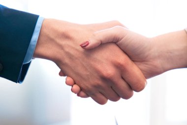 İki elin sıkıştığı, başarılı bir anlaşmayı ya da ortaklığı simgeleyen yakın plan bir görüntü. Mesleki kıyafet kurumsal ya da iş ortamında güven ve işbirliği göstergesi olarak belirtilir..