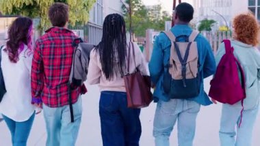 Kampüste elinde kitap ve klasörlerle dolaşıp gülümseyen ve konuşan bir grup öğrenci. Eğitim, takım çalışması, gençlik, çeşitlilik ve üniversite hayatı gibi konular için ideal.