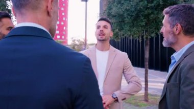 Çağdaş bir ofis binasının dışında değişik profesyonellerden oluşan bir grup canlı bir tartışma yapıyor. İş ortamında işbirliği ve takım çalışması.