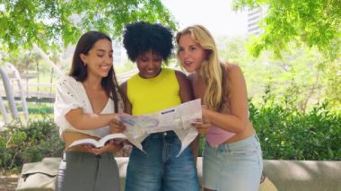 Üç neşeli kadından oluşan bir grup, açık hava ortamında gezmek ve gülümsemek için bir harita kullanıyor. Yolculuk, macera ve dostluk temaları için mükemmel. Canlı ve güneşli yaz atmosferleri..