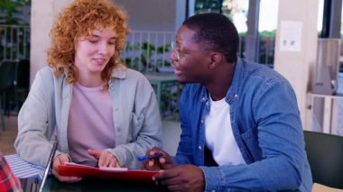 Öğrenciler modern bir açık hava ortamında tablet kullanarak birlikte çalışıyorlar. Odaklanmış ifadeleri ve günlük kıyafet vurgu takım çalışması, öğrenme ve profesyonel ama rahat bir ortamda işbirliği