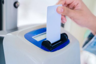 Toplu taşıma makinesine bilet sokan bir elin yakın çekimi. Elektronik cihaz giriş biletini tarıyor. Modern banliyö ve ulaşım sistemi kavramı.