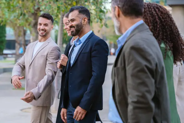 Modern bir ofis binasının önünde birlikte yürüyen çeşitli iş adamları. Sohbete dalarlar, resmi ve şık giyinirler..