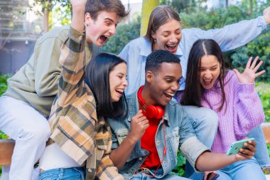 Bir grup öğrenci üniversite kampüsünde buluşup arkadaşlarıyla video görüşmesi yapıyor. Eğitim, üniversite hayatı konsepti.