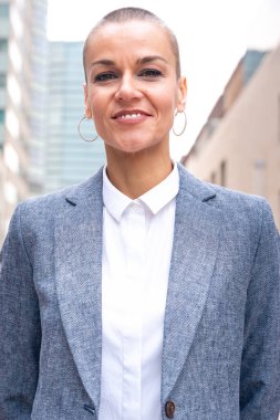 Beyaz bir iş kadınının dış mekanda duran takım elbisesiyle kameraya mutlu bakışları. Düşünceli bir ifadeyle genç bir avukatın bakışları.