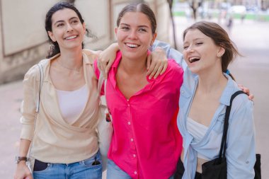 Üç mutlu dedikoducu genç dışarıda sohbet ediyor. Bir grup Kafkasyalı arkadaş sohbet edip iletişim kuruyor. Genç yetişkin öğrenciler sosyal bir toplantıda gülümsüyor ve birlikte yürüyorlar..