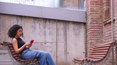 Kıvırcık saçlı, pembe ceketli, şehir ortamında hareket ve enerji ifade eden Afrikalı Amerikalı dansçı. Modern moda, çağdaş dans ve sanatsal performans.