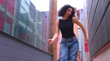 Afro-Amerikalı bir kadın şehir ortamında banklar arasında yaratıcı bir pozda dans ediyor. Günlük kıyafetler giyiyor ve denge, güç ve ifade gösteriyor. Hareket, sanat ve özgürlük kavramı. 