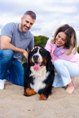 Neşeli çift kumlu bir plajda köpekleriyle vakit geçiriyor. Doğada barışçıl bir anın tadını çıkarırken gülümser ve bağlanırlar. Parçalı bulutlu bir gökyüzünün altında kürklü eşleriyle. Dikey